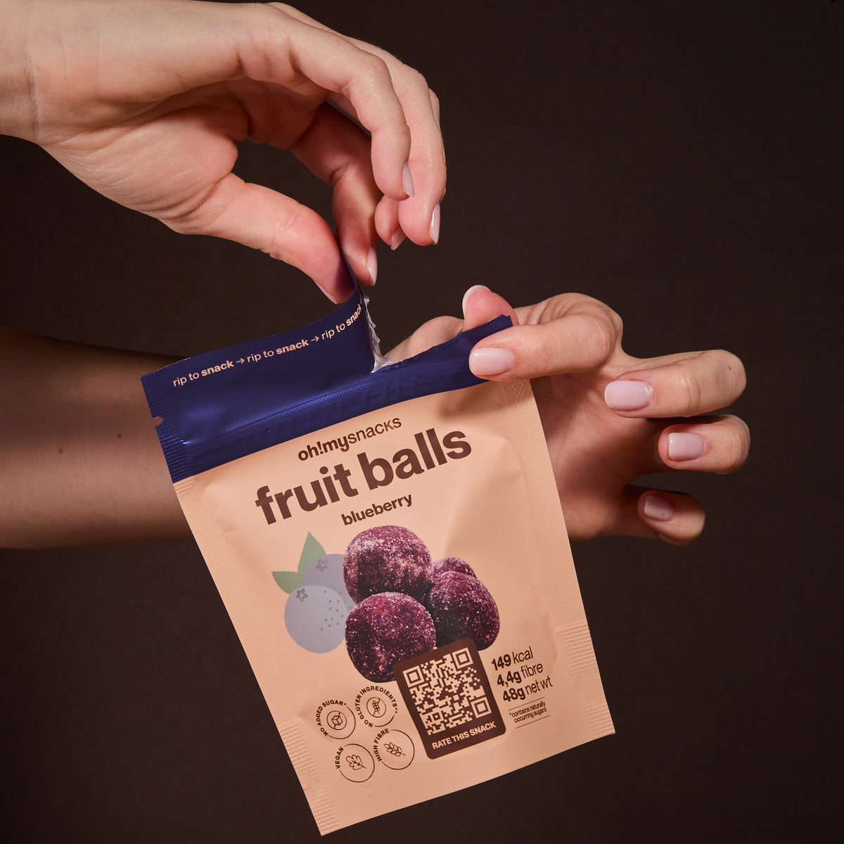 Hands opening a Fruit Balls Blueberry packet