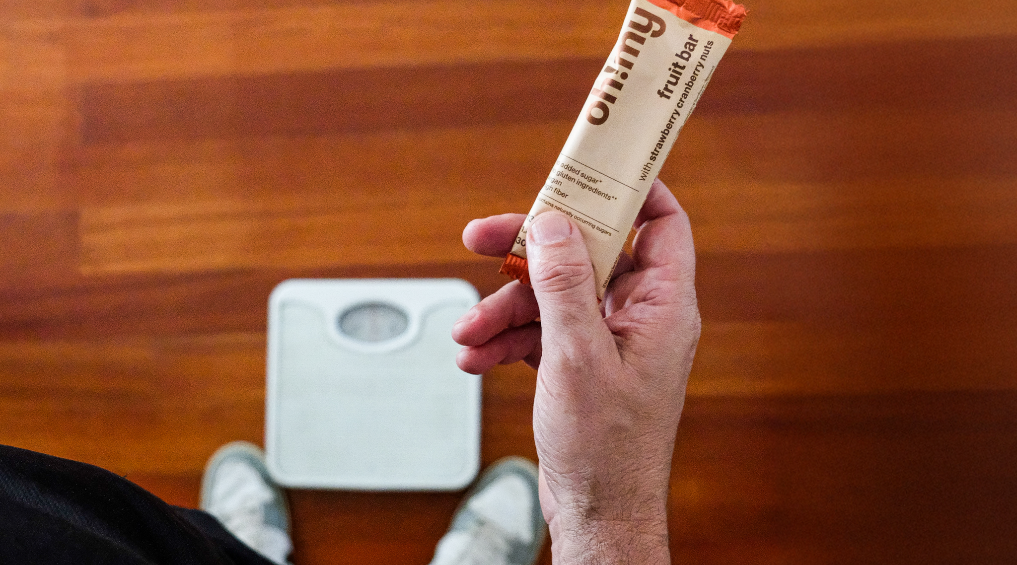 man with snack bar measuring his weight on a scale