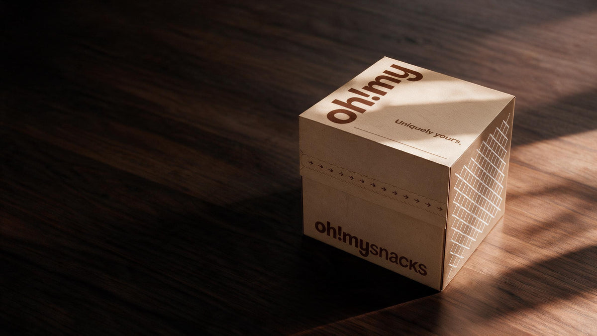 A closed Oh!My box on an oak table, in late-afternoon sun