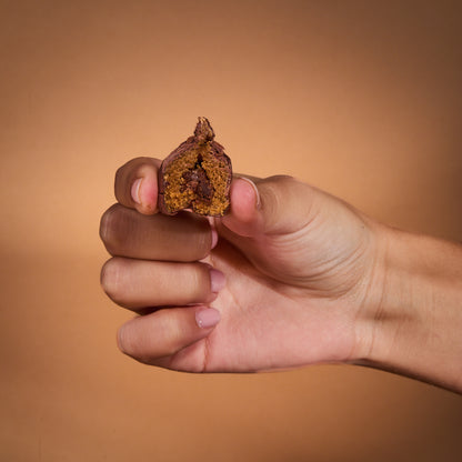 A hand holding Cocoa Coated Protein Balls Cocoa Cream, showing the inside