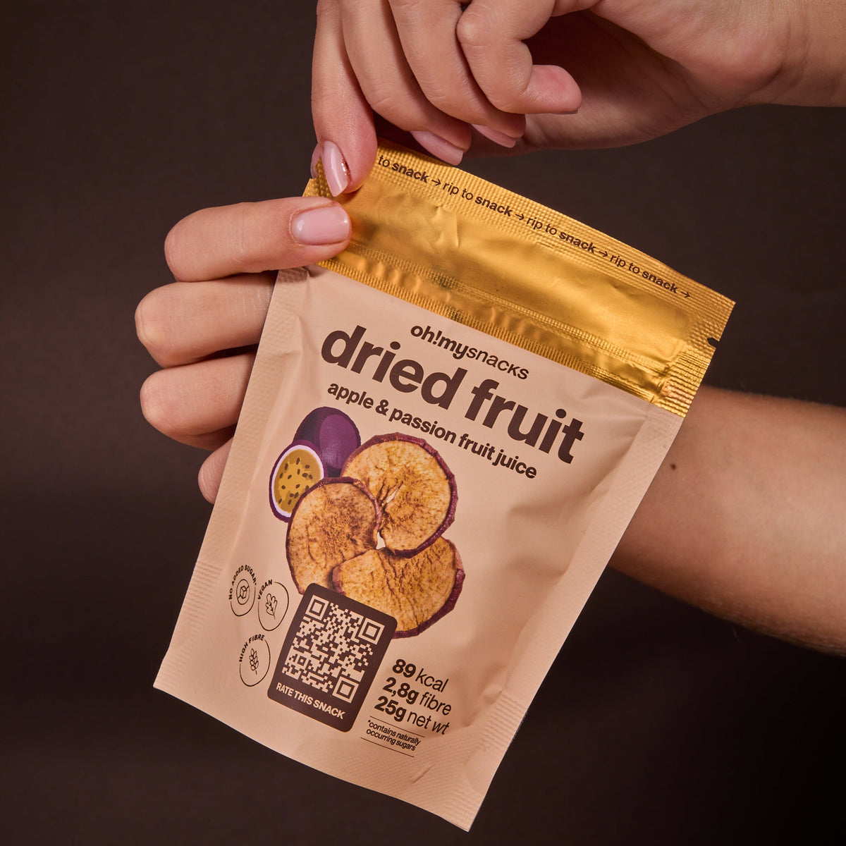 A hand holding a Dried Apple Passionfruit packet