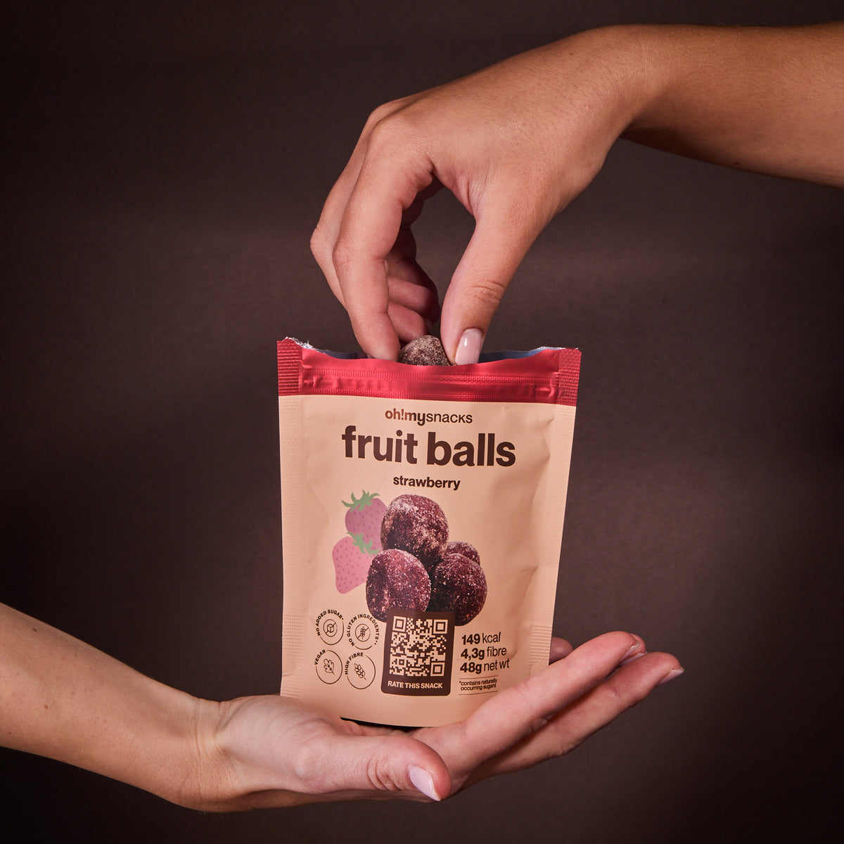 A hand taking Fruit Balls Strawberry out of the packet