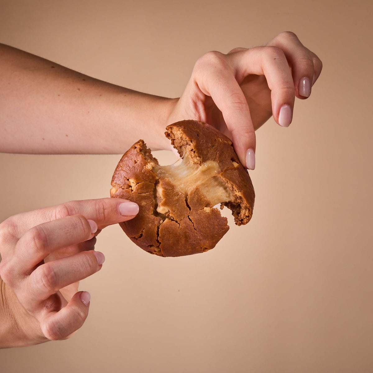 Hands breaking Protein Cake Caramel Cream in half