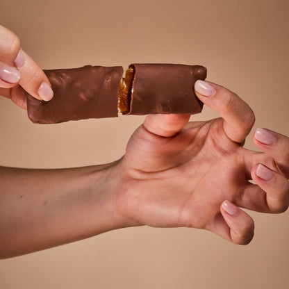 Hands breaking Protein Milk Chocolate with Salted Caramel in half