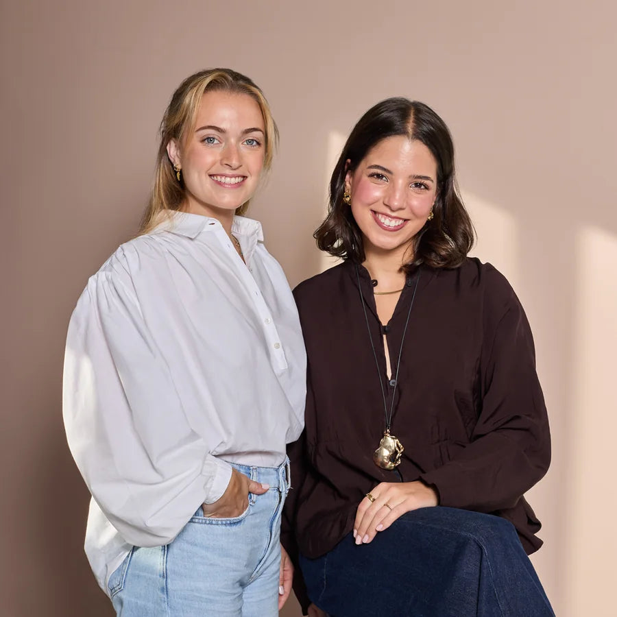 Matilde and Mafalda, from our nutrition team, smiling against a pink wall
