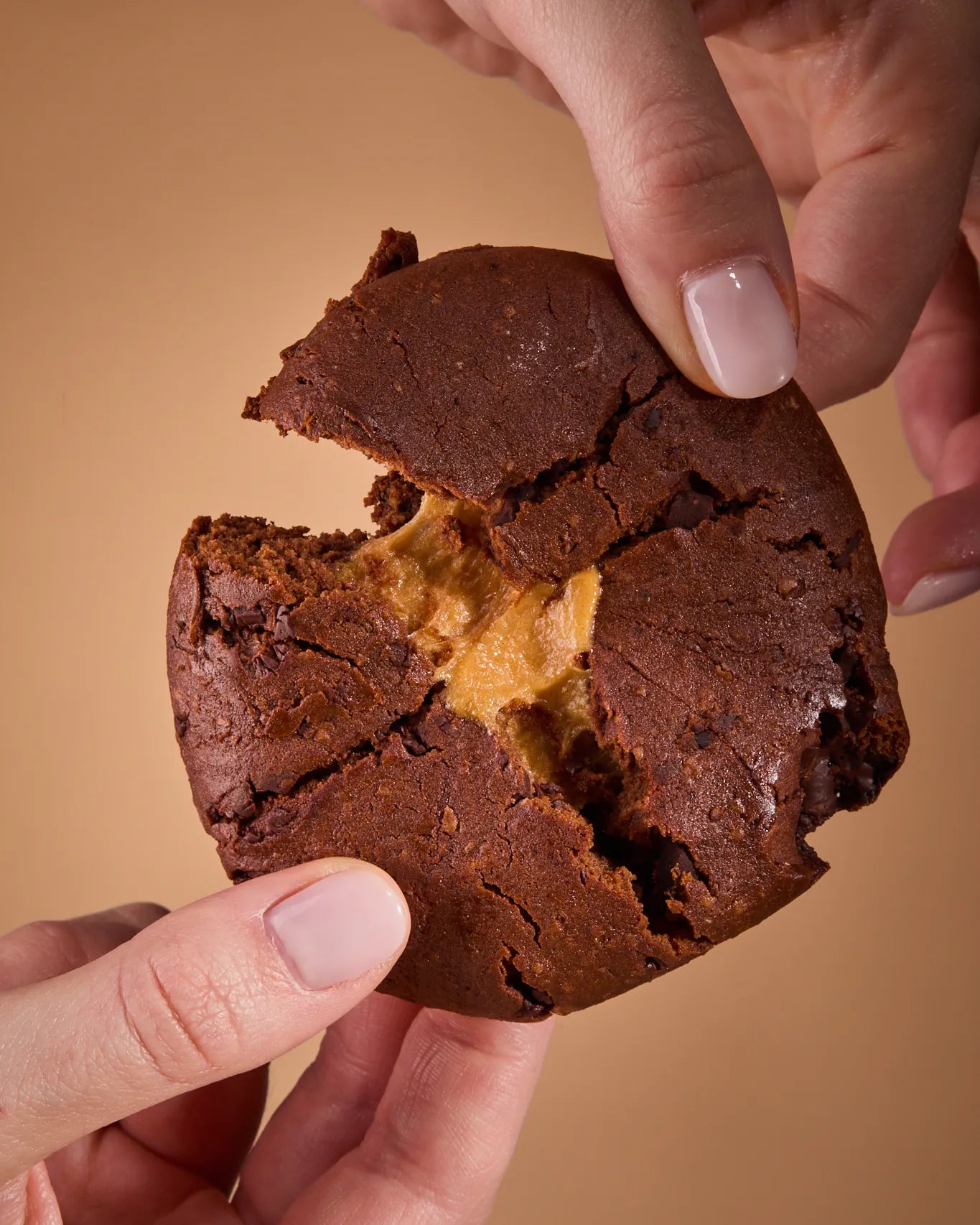 Two hands breaking a Protein Cake Vanilla Cream in half, with the golden cream showing